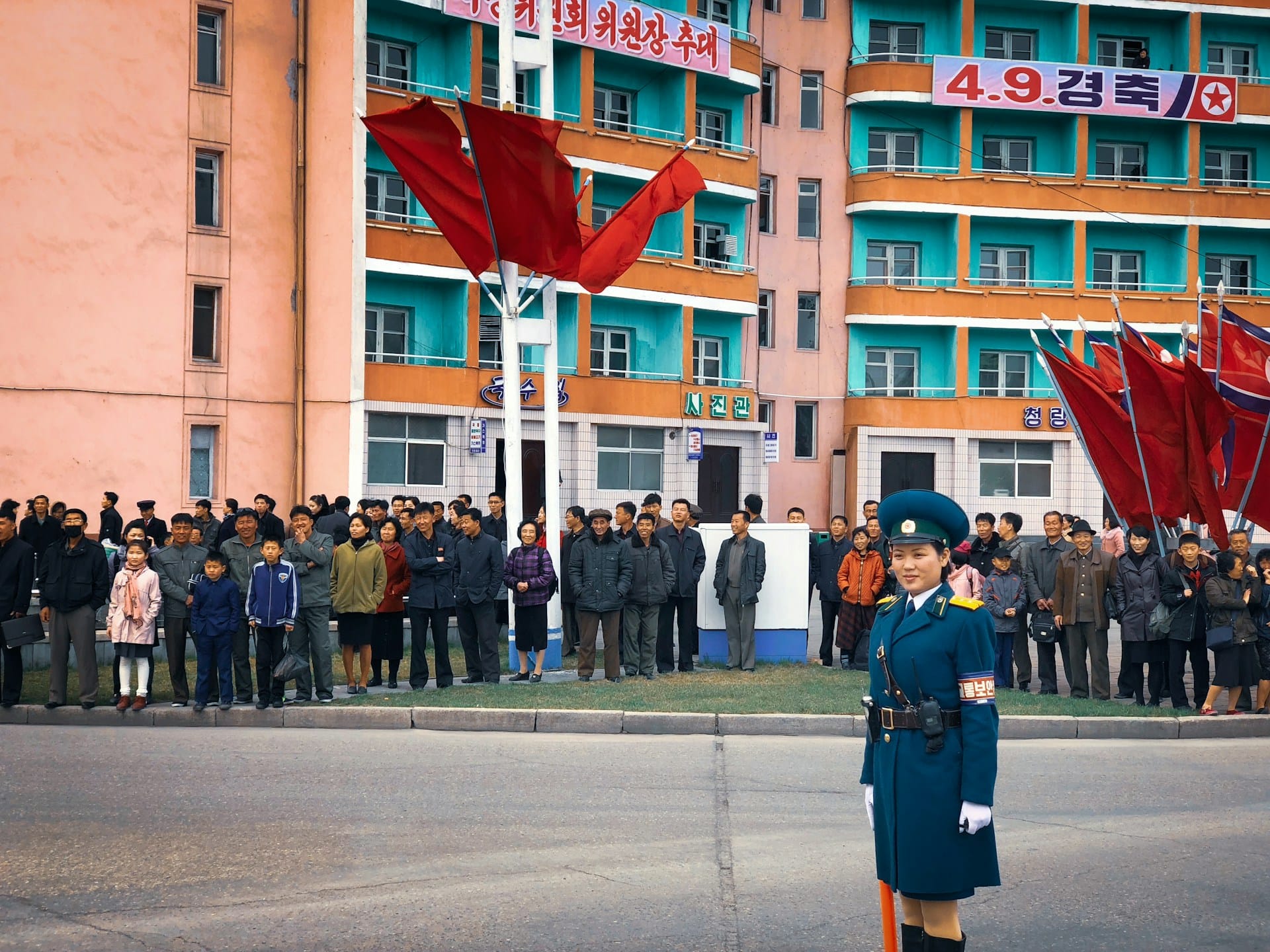 North Koreans stand by a road along with a traffic warden.